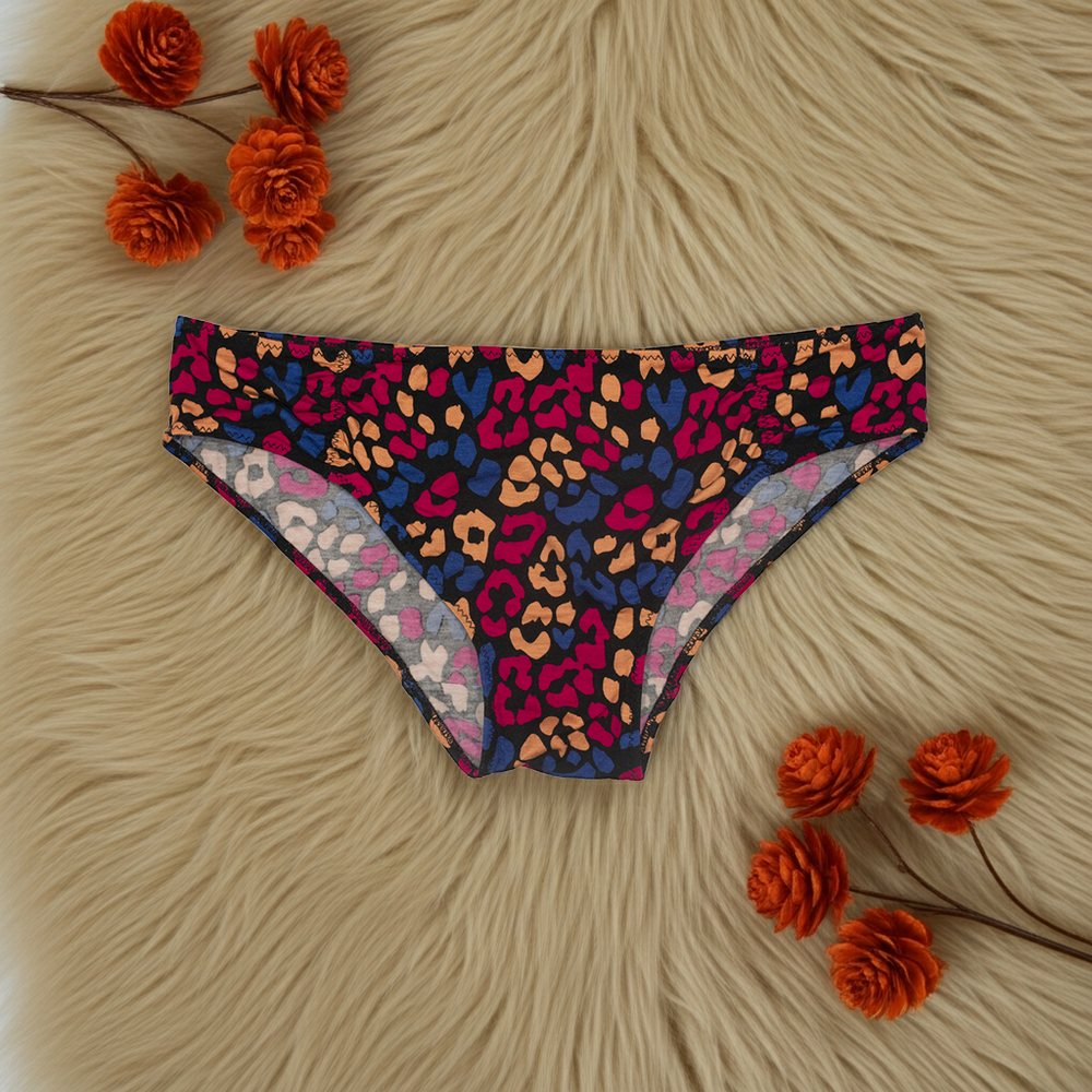 Colorful leopard print bikini bottom on a textured surface with orange flowers.